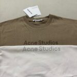 T-shirt Acne Studios two-tone bianca e marrone con logo riflettente elegante e moderno.
