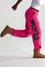 Persona in movimento con pantaloni rosa, stivaletti marroni e look casual dinamico.