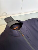 Giacca sportiva blu navy con dettaglio arancione, alto collo e chiusura a zip elegante.