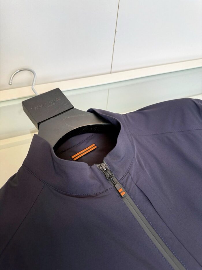 Giacca sportiva blu navy con dettaglio arancione, alto collo e chiusura a zip elegante.