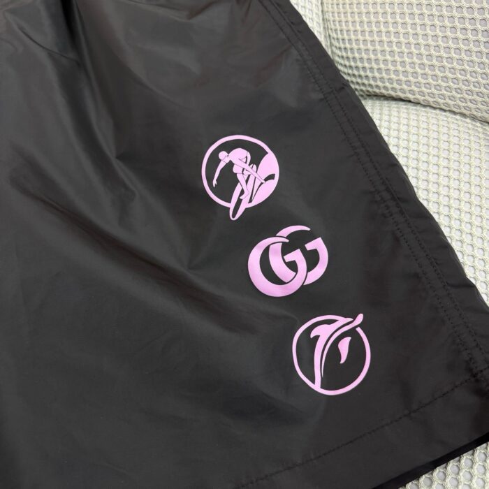 Giacca nera sportiva con loghi rosa vibranti e design moderno, perfetta per streetwear e outdoor.