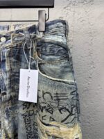 Jeans in denim con graffiti artistici, dettagli distressed e etichetta moderna Acone Studios.