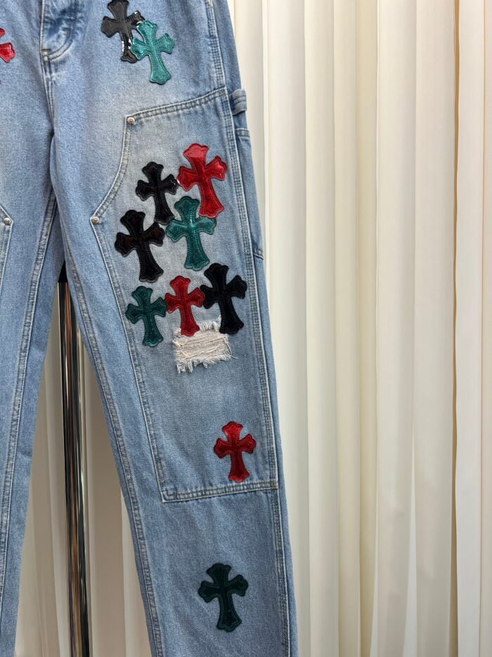 Jeans vintage con ricami di croci colorate e dettagli distressed, stile casual e artistico.