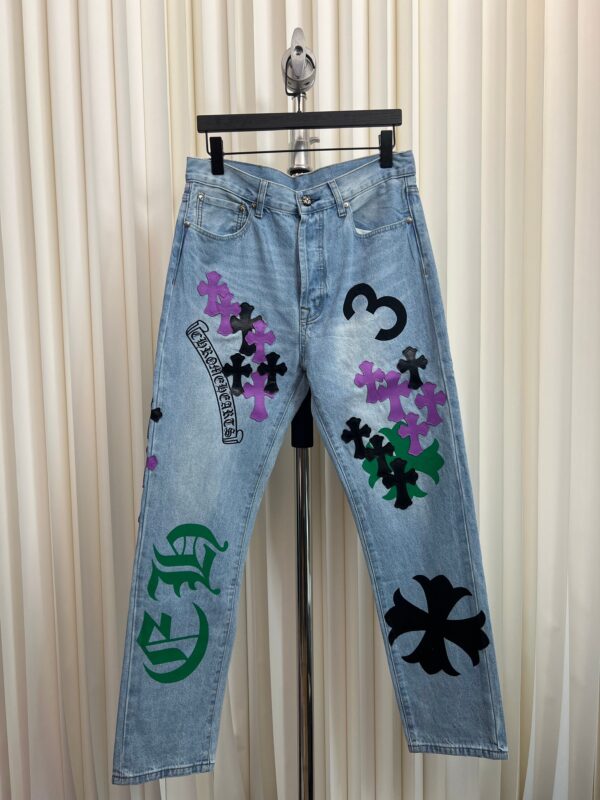 Jeans colorati con grafiche artistiche, fiori, numeri e simboli, stile casual e creativo.