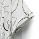 Camicia bianca con ricami astratti marroni, stile moderno e confortevole per ogni occasione.