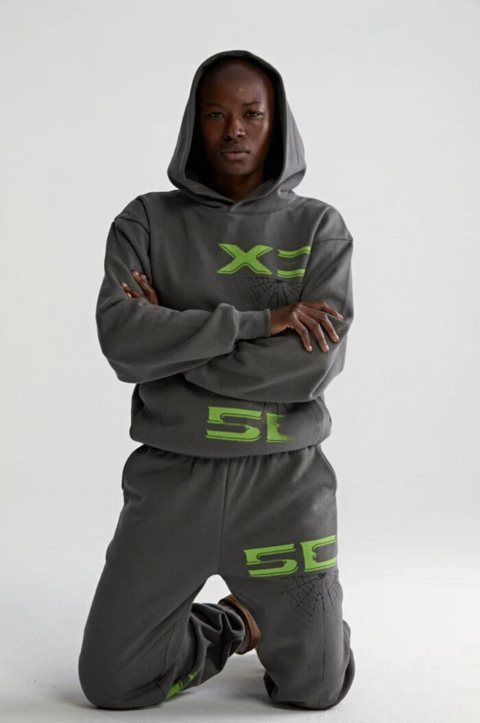 Modello in outfit athleisure grigia con dettagli neon verde, posa sicura e stile urbano moderno.