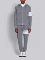 Outfit athleisure grigia con dettagli a strisce bianche e sneakers sportive, stile casual e moderno.