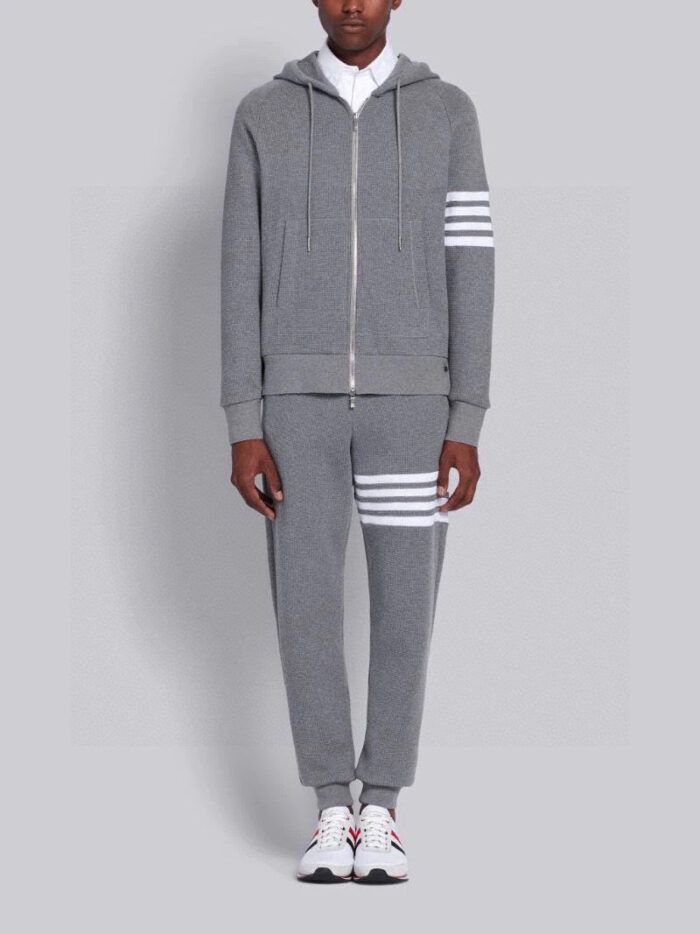 Outfit athleisure grigia con dettagli a strisce bianche e sneakers sportive, stile casual e moderno.