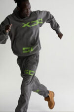 Persona in movimento con outfit athleisure grigio e dettagli neon verdi, stile sporty e moderno.