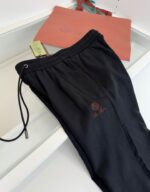 Pantaloni sportivi neri con logo rosso e borsa corallo, stile casual e athleisure elegante.