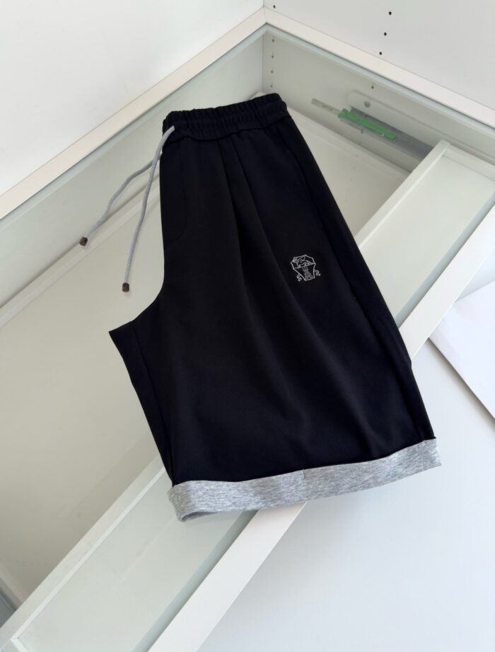 Pantaloncini sportivi neri con orlo grigio, elastico e logo sottile, ideali per allenamento e casual.