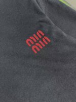 Tessuto sportivo nero con logo rosso dinamico, stile moderno e adatto a abbigliamento casual e athleisure.