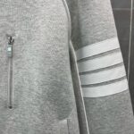 Felpa sportiva grigia con zip e dettagli lucidi, ideale per casual e sportiva quotidiana.