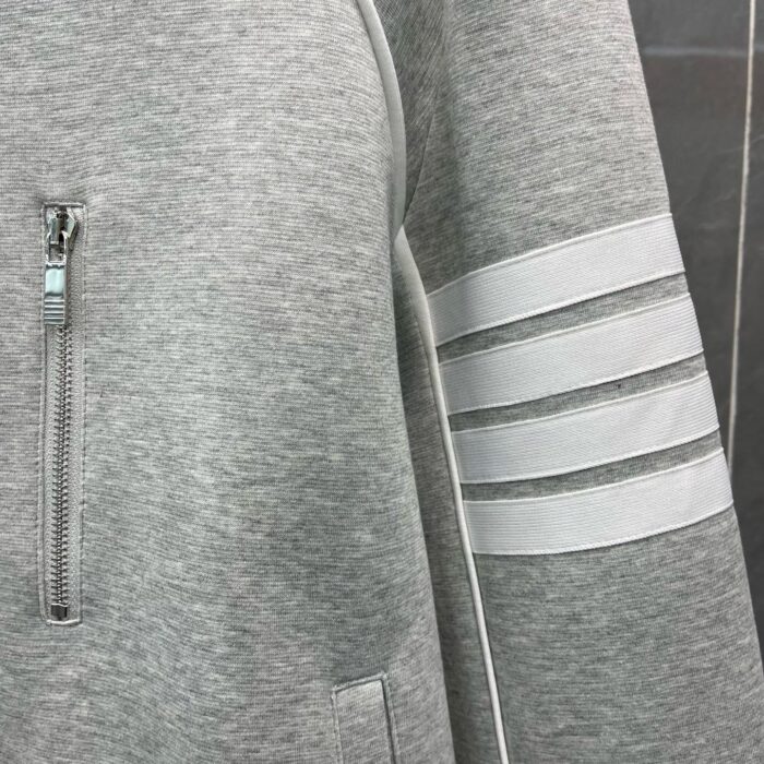 Felpa sportiva grigia con zip e dettagli lucidi, ideale per casual e sportiva quotidiana.