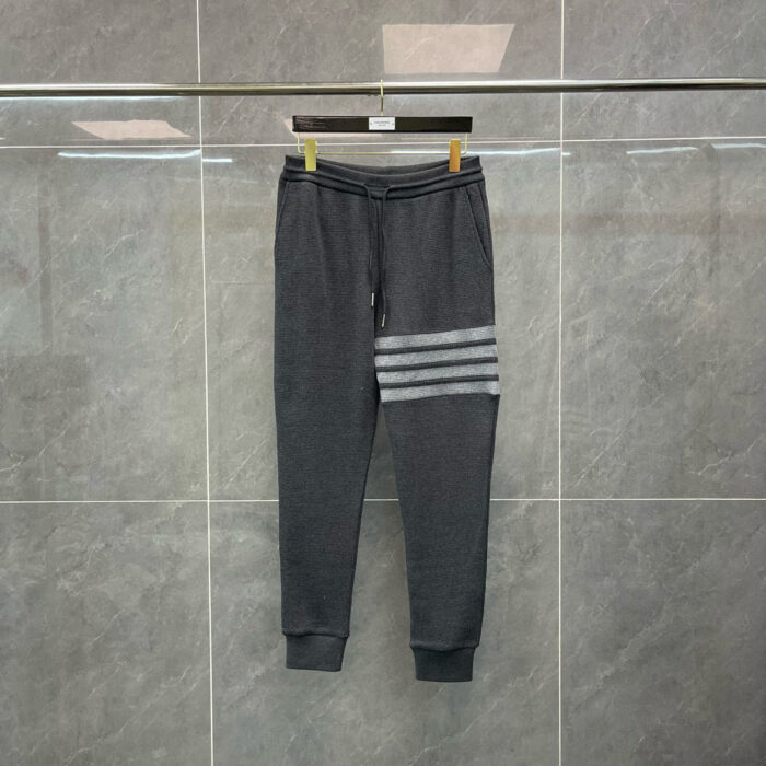 Pantaloni jogger sportivi grigi con strisce contrastate, elastici in vita e polsini stretti.