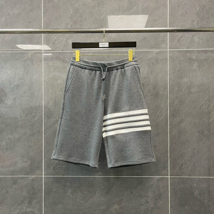 Shorts sportivi grigi con strisce bianche e cinturino elastico, perfetti per attività casual.