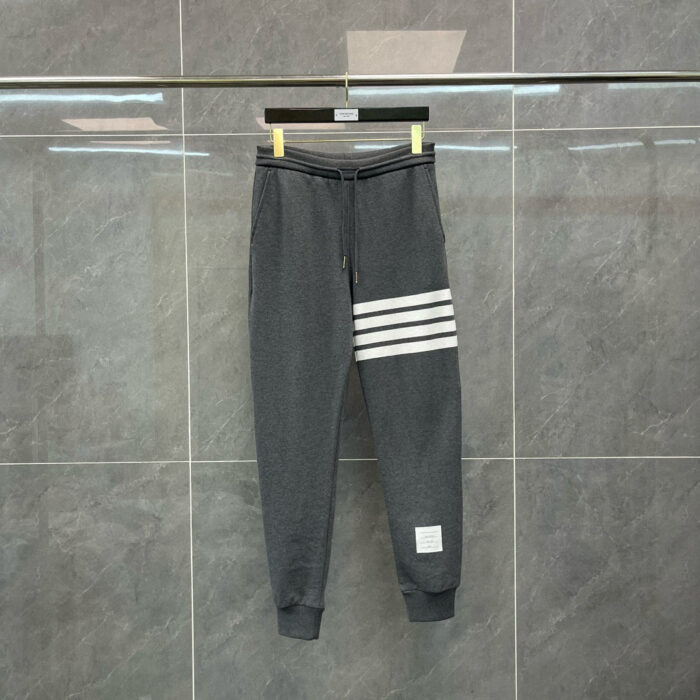 Pantaloni sportivi grigi con strisce bianche, elastico in vita e stile casual moderno.