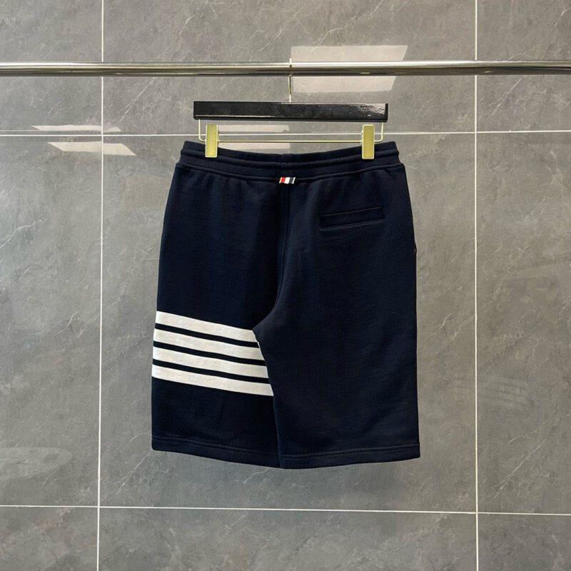 Pantaloncini sportivi navy con strisce bianche, logo e tasca posteriore, stile athleisure.