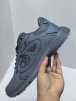 Scarpa sportiva moderna grigia unisex con suola antiscivolo e logo embossato, ideale per sport e casual.