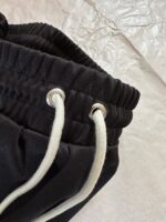 Pantaloni jogger neri con coulisse in tessuto elasticizzato e dettagli metallici eleganti.