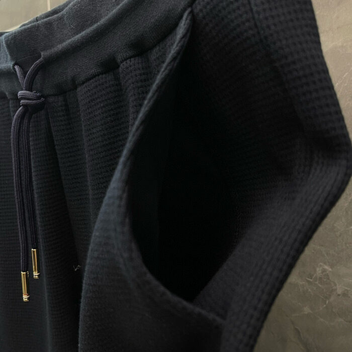 Pantaloncini sportivi neri con fascia in tessuto a griglia e coulisse in metallo.