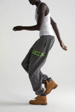 Modello in movimento con joggers neon, canotta bianca e stivaletti rugged urban.