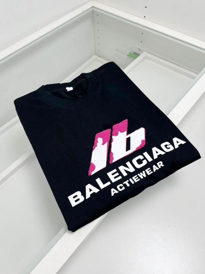 T-shirt Balenciaga nero con logo rosa, stile activewear, moda uomo elegante e trendy.