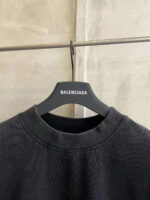 Felpa nera Balenciaga, scollatura relax, stile urbano minimalista con brand su appendiabiti moderno.