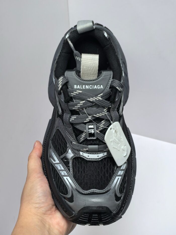 Sneakers Balenciaga futuristiche nere con suola robusta, dettagli riflettenti e design sportivo moderno.