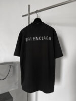 Maglietta nera oversize Balenciaga con logo sgranato sul retro, stile streetwear minimalista e urbano.