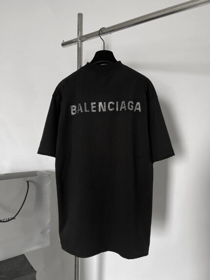 Maglietta nera oversize Balenciaga con logo sgranato sul retro, stile streetwear minimalista e urbano.