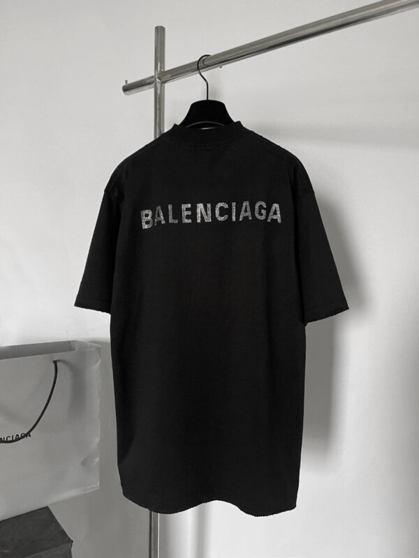 Maglietta nera oversize Balenciaga con logo sgranato sul retro, stile streetwear minimalista e urbano.