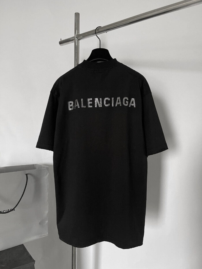 Maglietta nera oversize Balenciaga con logo sgranato sul retro, stile streetwear minimalista e urbano.