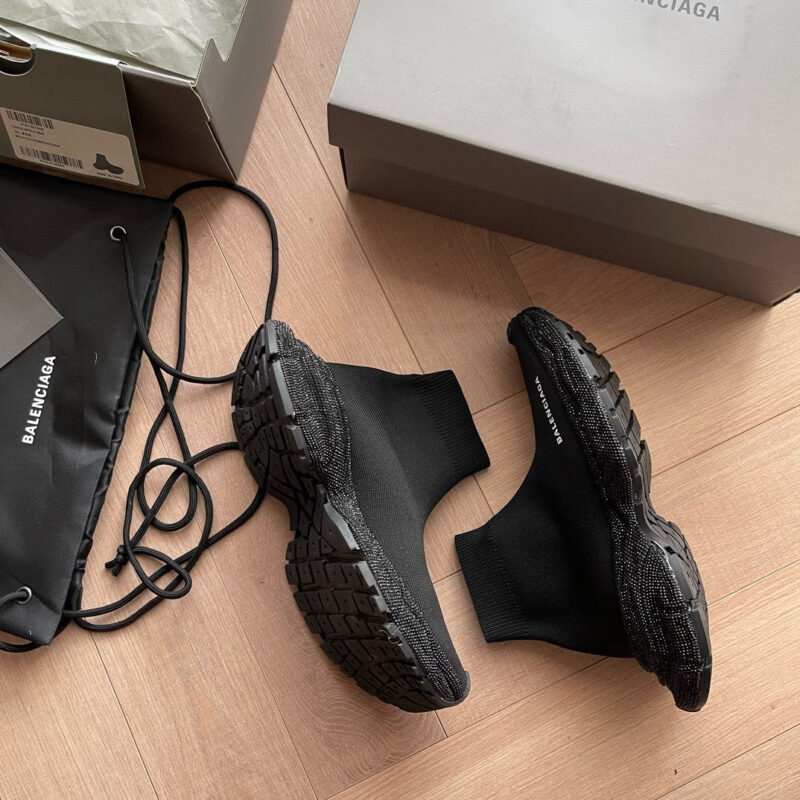 Sneakers nere Balenciaga con packaging di lusso su pavimento in legno elegante.