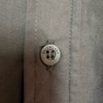 Button Balenciaga di alta moda su camicia elegante, dettagli raffinati e qualità superiore.