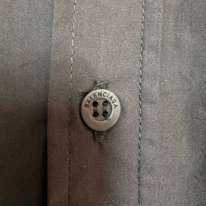 Button Balenciaga di alta moda su camicia elegante, dettagli raffinati e qualità superiore.