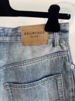 Jeans Balenciaga in denim chiaro con cuciture detailing e patch in pelle, stile casual di lusso.