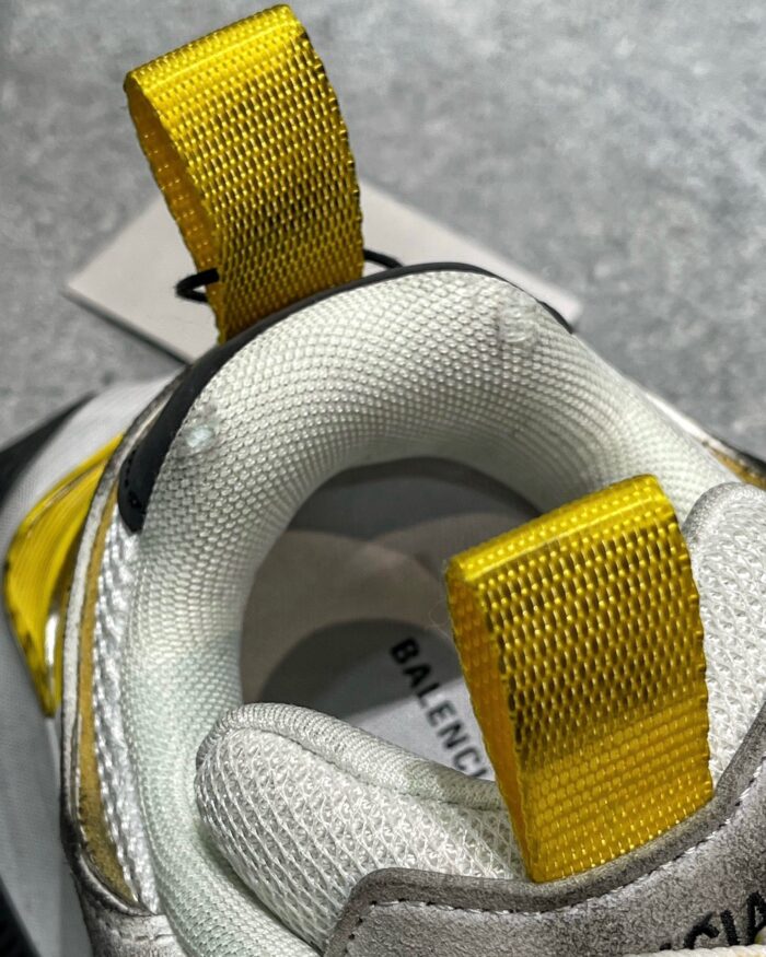 Sneaker Balenciaga moderna con logo, tallone giallo, design elegante e comfort elevato.