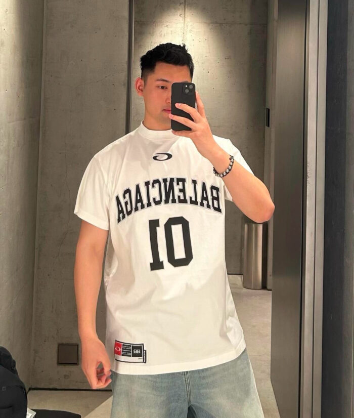 Selfie in stile streetwear con jersey Balenciaga e jeans denim in ambiente minimalista moderno.