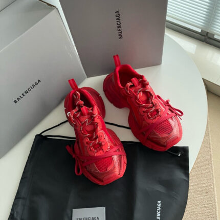 Sneakers rosse Balenciaga con scatole grigie e dust bag in ambiente elegante e luminoso.