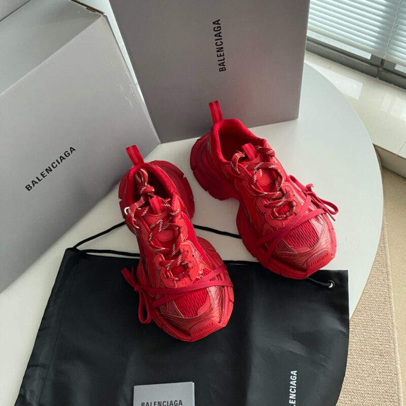 Sneakers rosse Balenciaga con scatole grigie e dust bag in ambiente elegante e luminoso.