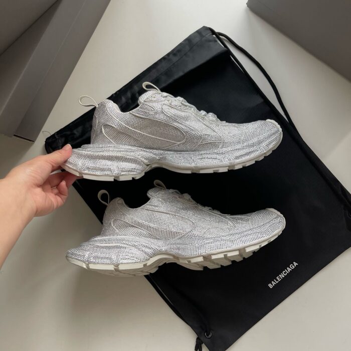 Sneaker Balenciaga argentate e borsa di lusso moderna su sfondo bianco.