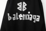 Felpa nera Balenciaga con scritte metalliche brillanti e design moderno streetwear.