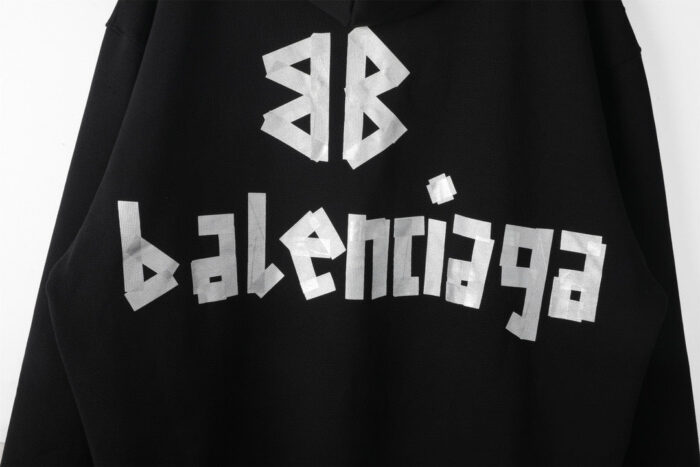 Felpa nera Balenciaga con scritte metalliche brillanti e design moderno streetwear.