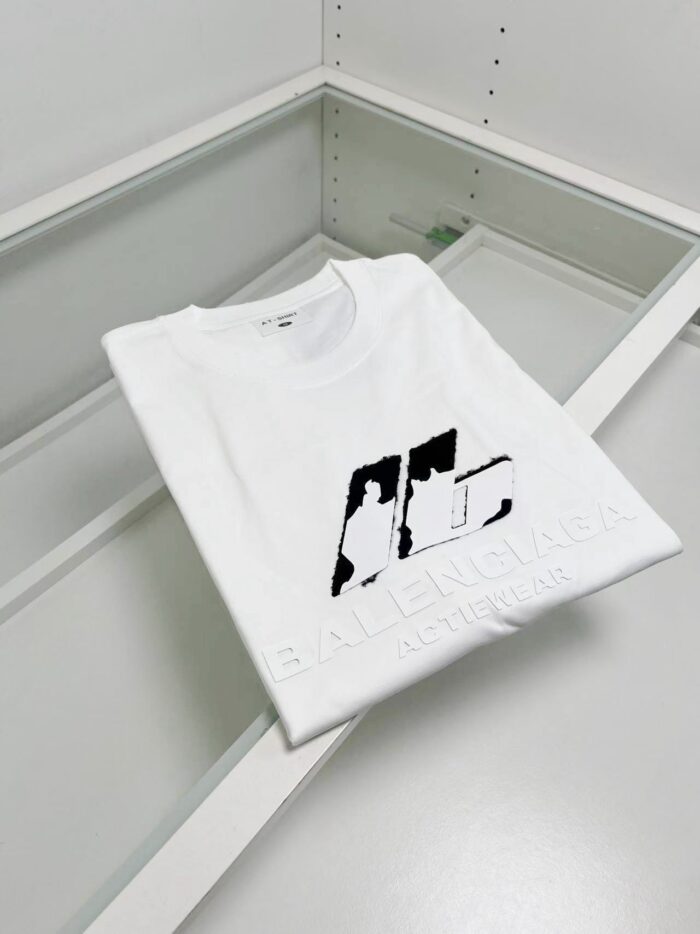 T-shirt bianca Balenciaga con grafica moderna in esposizione minimalista di alta moda.