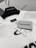 Maglietta bianca Balenciaga con logo nero, etichette eleganti e presentatione minimalista raffinata.