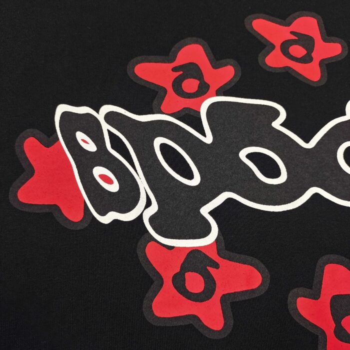 T-shirt streetwear BAPE con logo bianco e stelle rosse su sfondo nero, stile urbano.