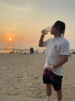 Uomo rilassato in spiaggia al tramonto, scena di relax e bellezza naturale.