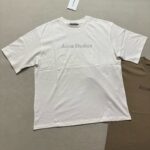 Maglietta off-white Acne Studios casual e moderna, con logo minimalista e tag visibile.