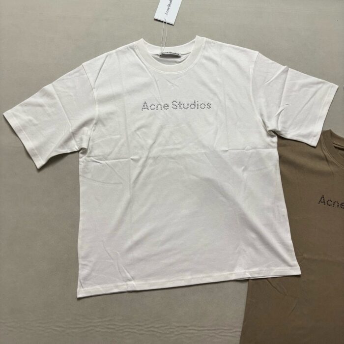 Maglietta off-white Acne Studios casual e moderna, con logo minimalista e tag visibile.